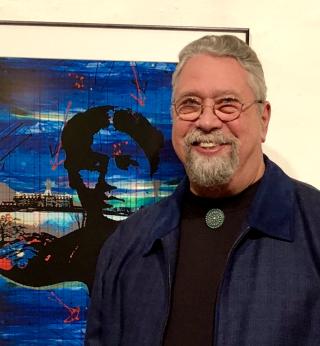 Gerry Lang standing in front of a blue toned art piece. Image provided by the artist.