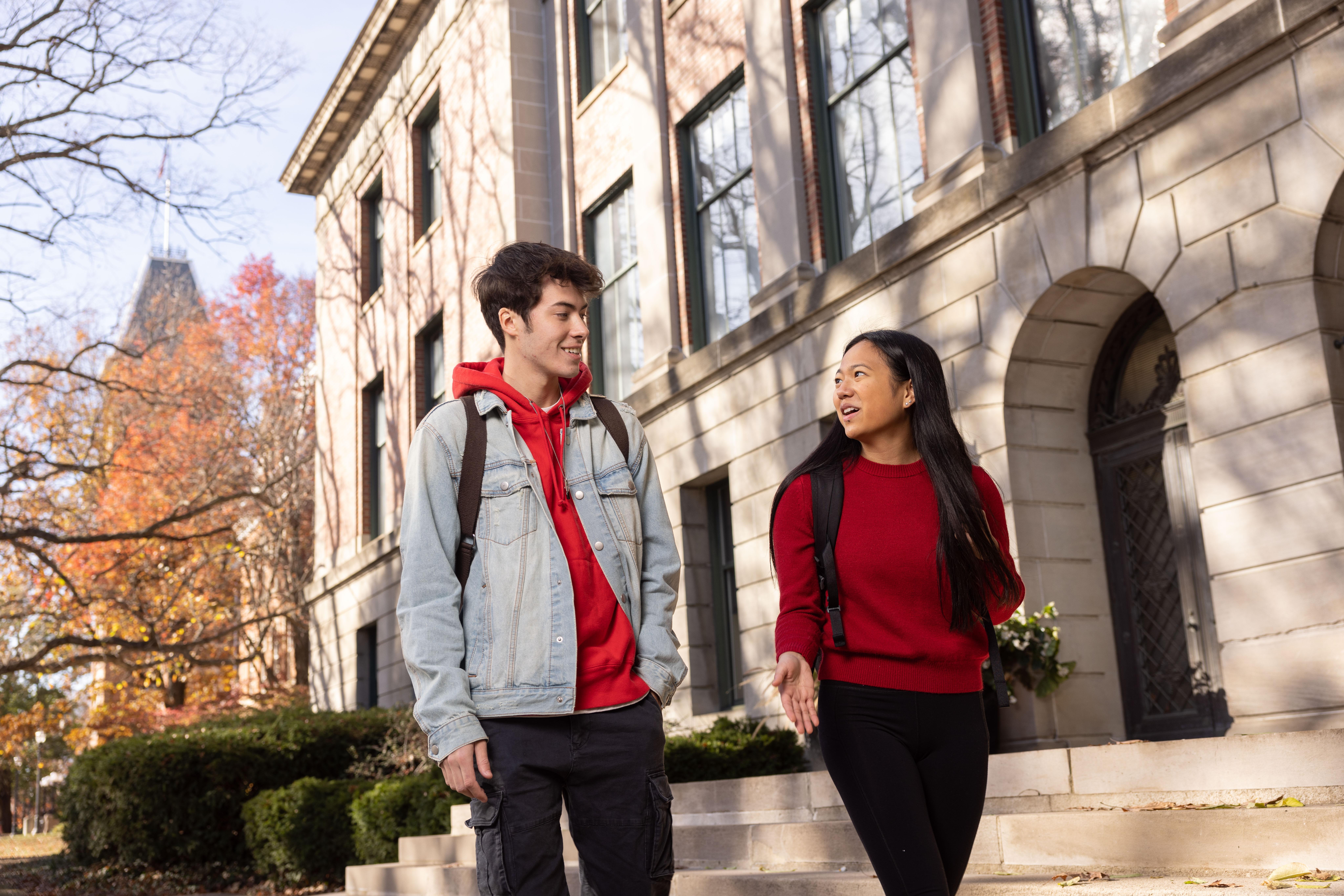 Two students walking outside across campus in fall